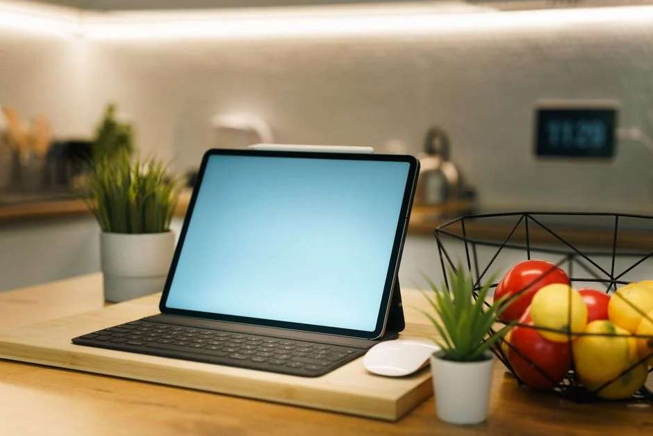 Gros plan sur des mains tapant sur un ordinateur portable, à côté d’une tasse de café posée sur un bureau en bois.